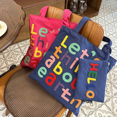 Une lettre brodée en couleurs, un sac à l'épaule, un choix fonctionnel et à la mode