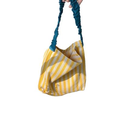 Un sac à épaule en toile à deux poignées avec des bandes contrastées accrocheuses