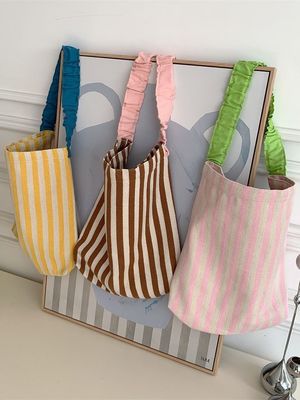 Un sac à épaule en toile à deux poignées avec des bandes contrastées accrocheuses