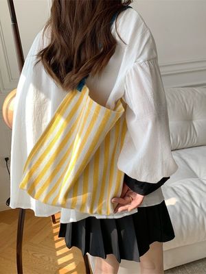 Un sac à épaule en toile à deux poignées avec des bandes contrastées accrocheuses