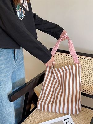 Un sac à épaule en toile à deux poignées avec des bandes contrastées accrocheuses