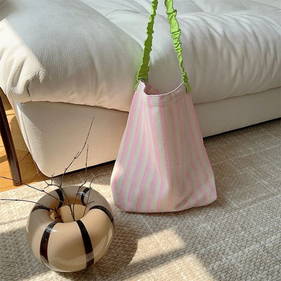 Un sac à épaule en toile à deux poignées avec des bandes contrastées accrocheuses